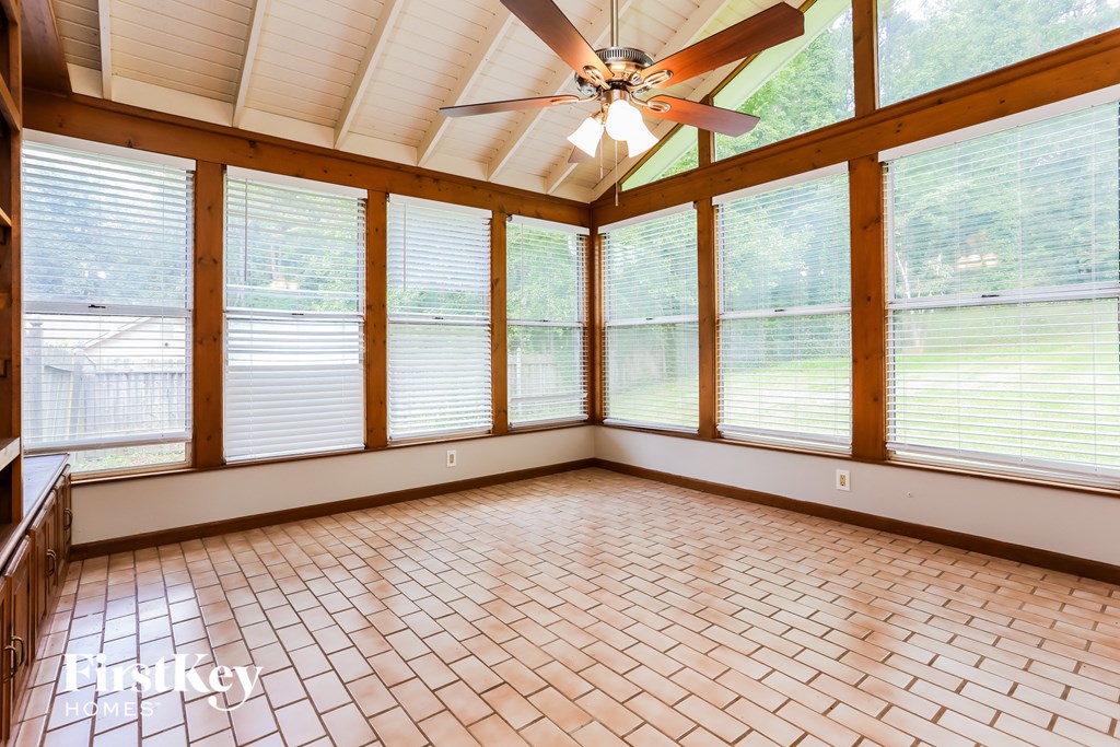 a sun room with large windows and a ceiling fan