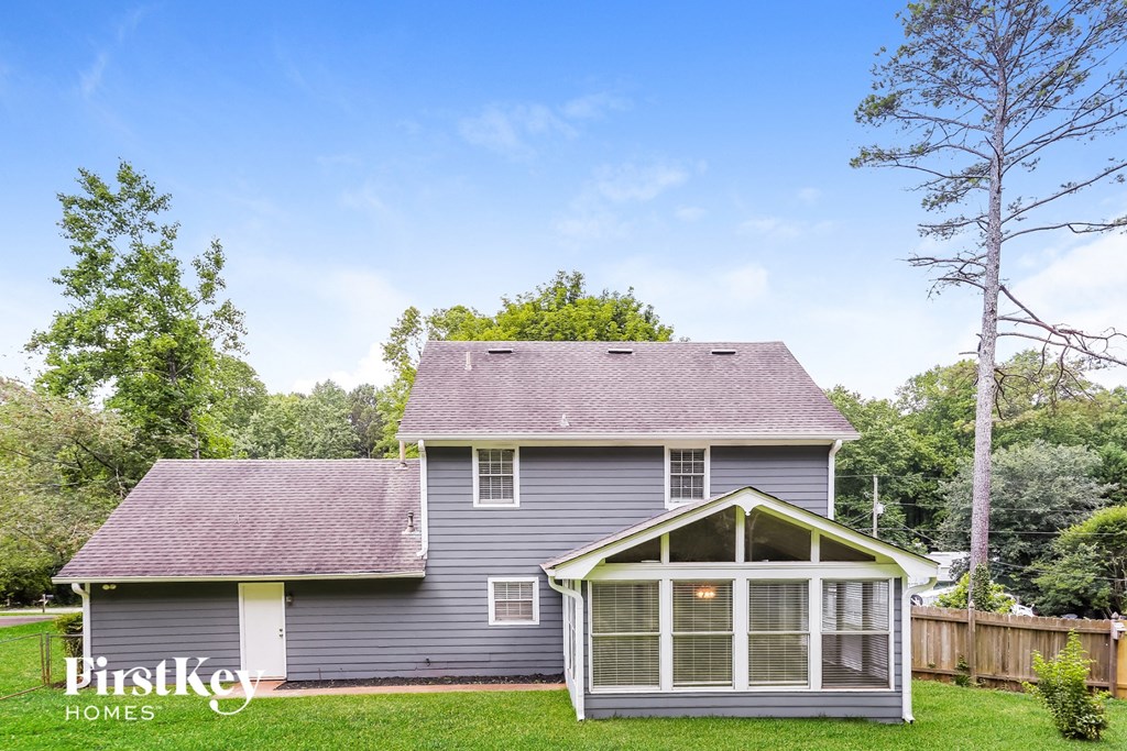 a small gray house with a porch and a yard