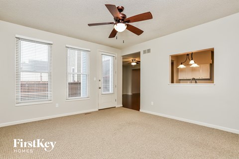 an empty living room with a ceiling fan and windows
