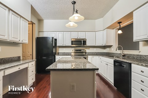 a kitchen with white cabinets and black appliances and granite counter tops