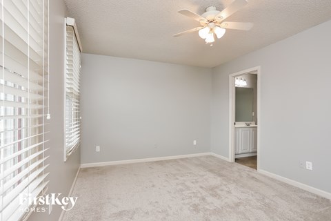 a spacious living room with white blinds and a ceiling fan