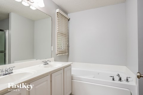 a white bathroom with a tub and a sink and a mirror