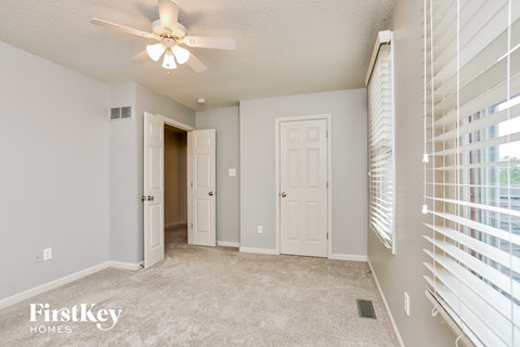 a spacious living room with white blinds and a ceiling fan