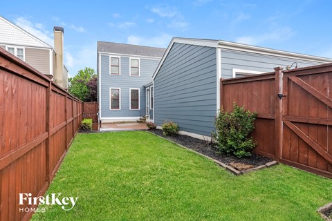 a backyard with a blue house and a wooden fence