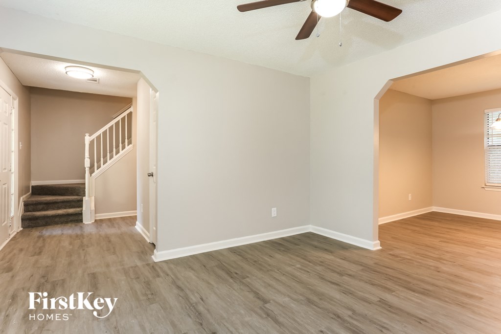 the living room of an empty house with wood floors and a ceiling fan