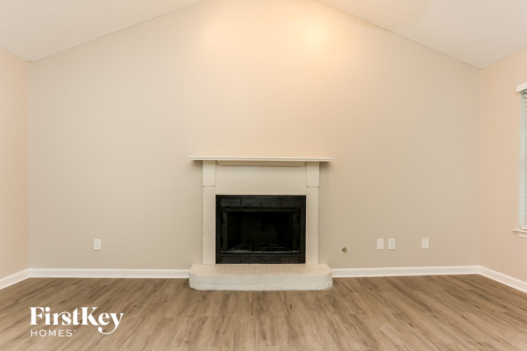 the living room of a home with a fireplace and wooden floors