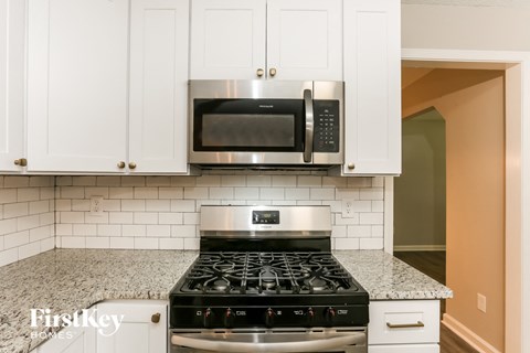 a kitchen with white cabinets and a stove and a microwave