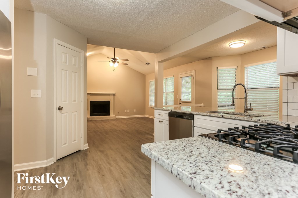 an open kitchen and living room with a fireplace and granite counter tops