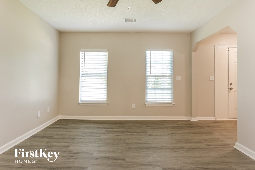 the living room of an empty house with wood floors and windows
