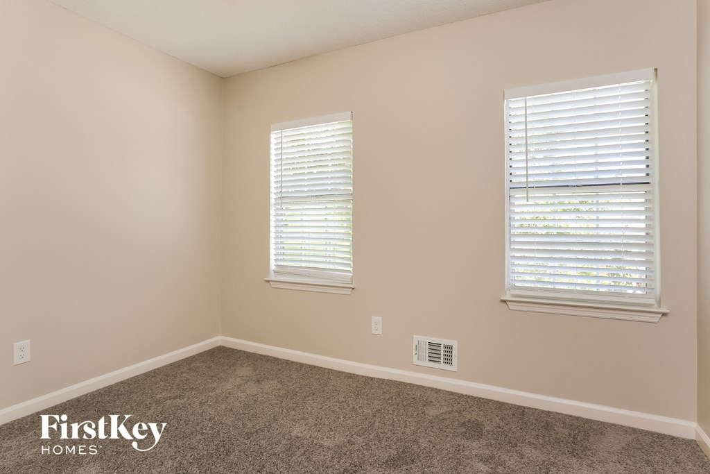 a room with carpet and two windows with blinds