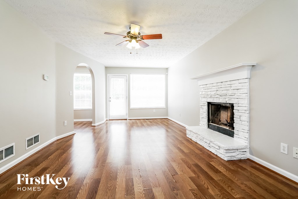 an empty living room with a fireplace and a ceiling fan