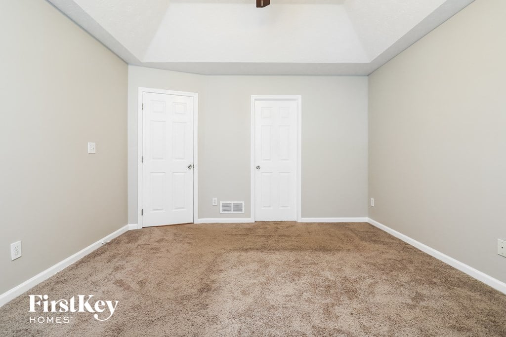 a carpeted room with two doors and a white ceiling
