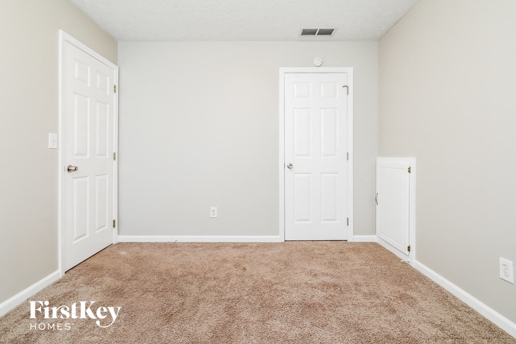 a bedroom with two doors and a carpeted floor
