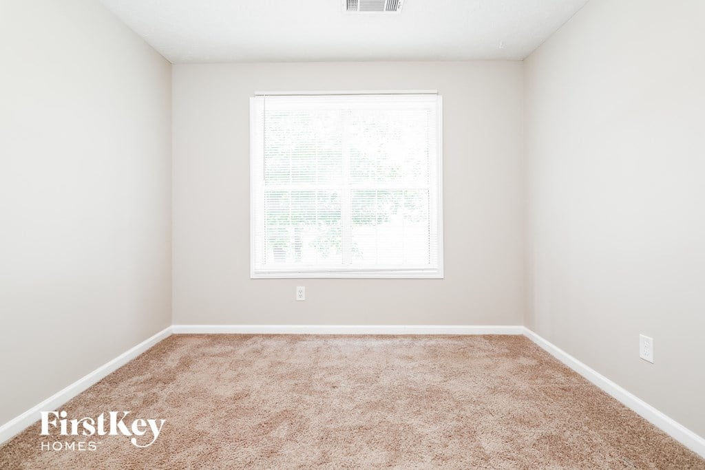 a spacious room with carpet and a window