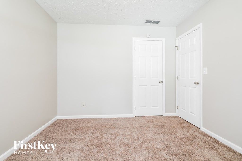 a bedroom with a carpeted floor and two doors