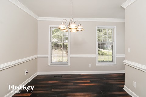 a empty dining room with a chandelier and two windows