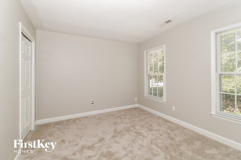 a bedroom with a carpeted floor and two windows
