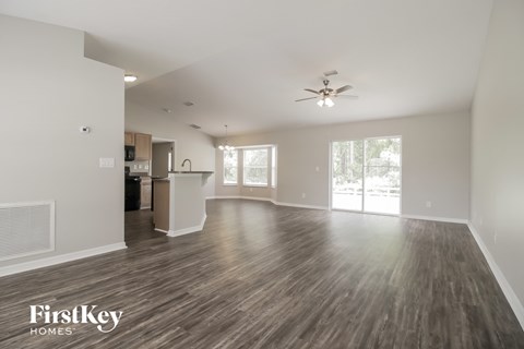 A spacious living room with wood flooring and a ceiling fan.