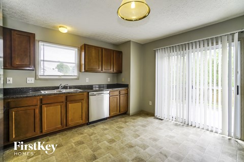A kitchen with wooden cabinets and a tiled floor.
