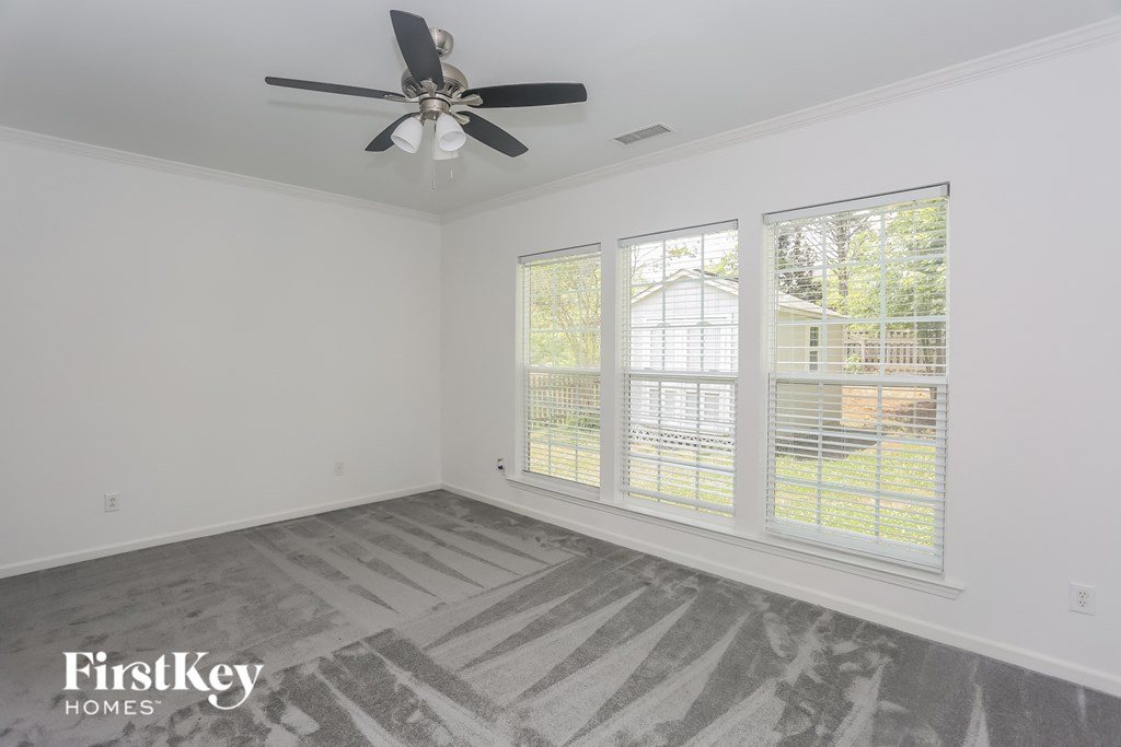 a bedroom with three windows and a ceiling fan