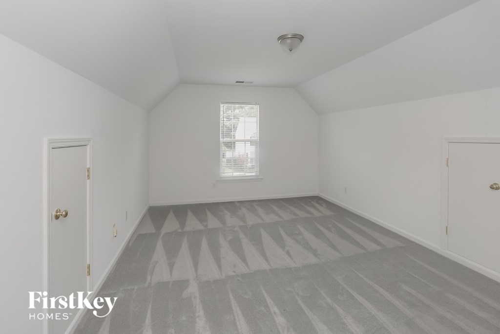 a bedroom with white walls and gray floors and a window