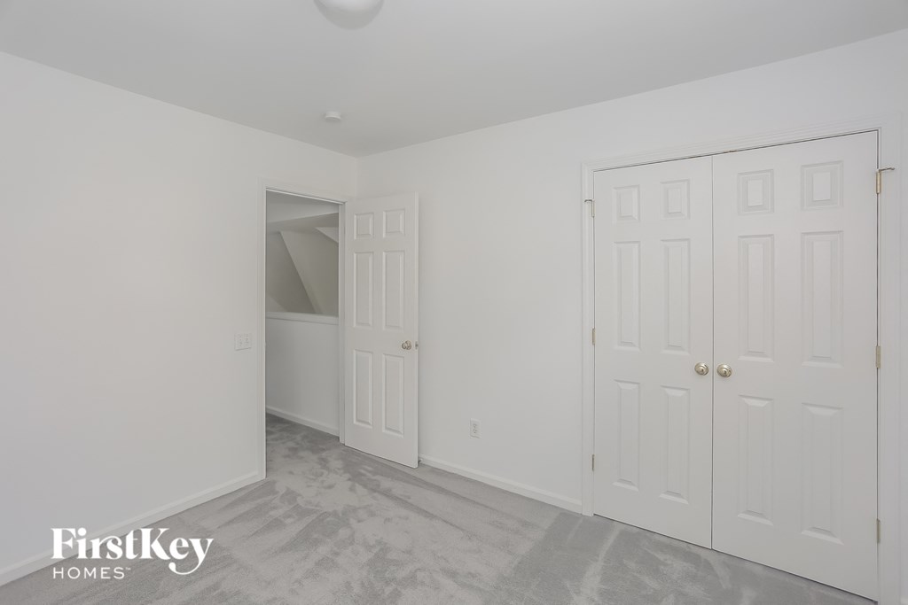 a bedroom with two closets and a white wall and a gray floor
