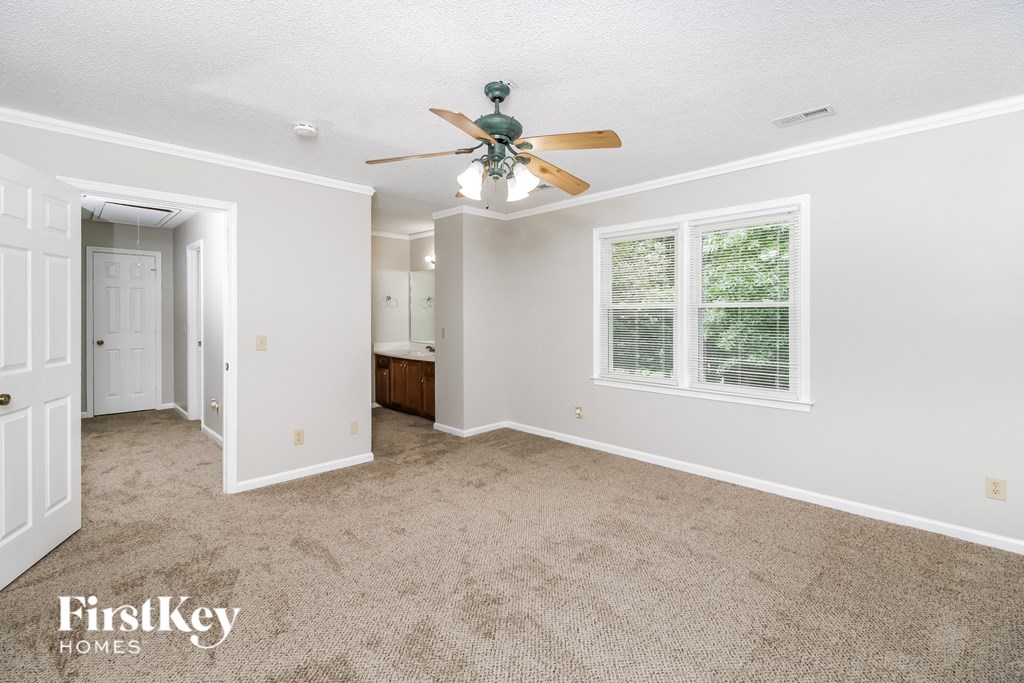 A spacious room with a ceiling fan and a window with blinds.