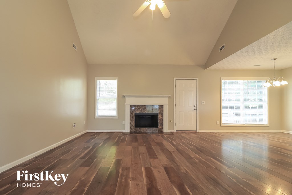 A spacious room with wooden floors and a fireplace.