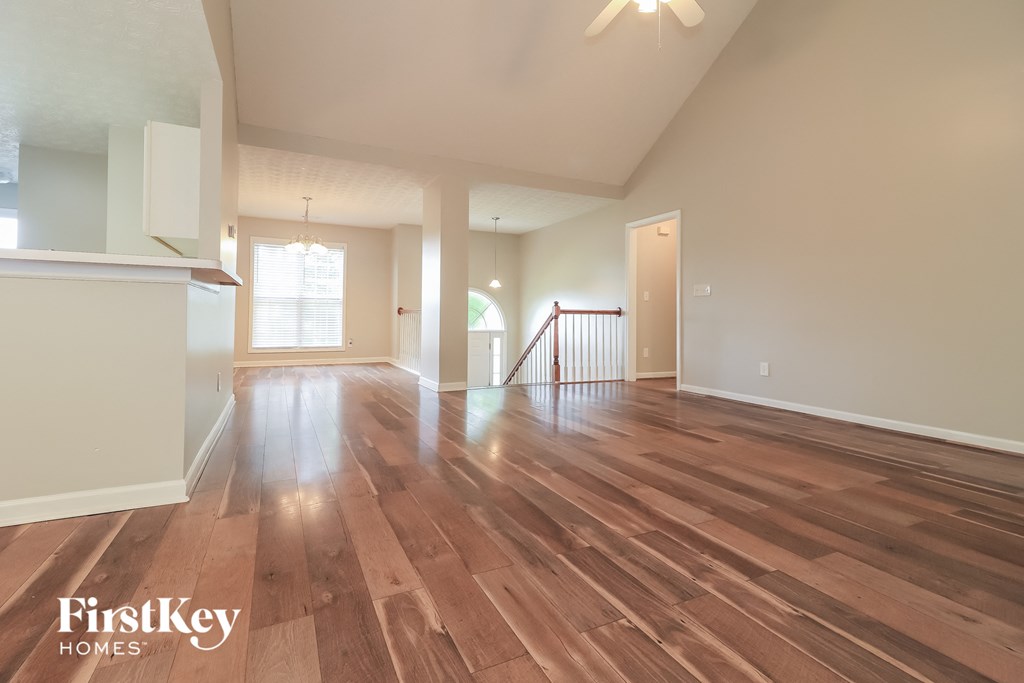 A spacious room with wooden flooring and a staircase.