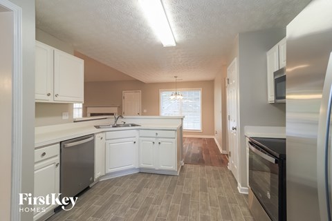 A kitchen with white cabinets and a wooden floor.