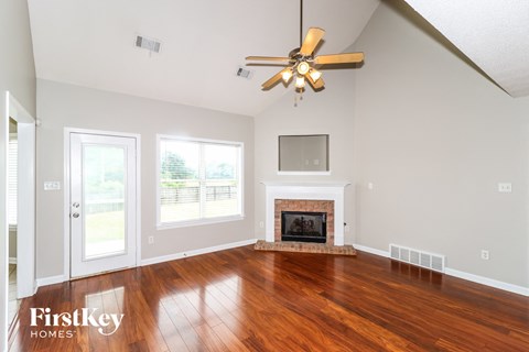 A spacious living room with a fireplace and a ceiling fan.