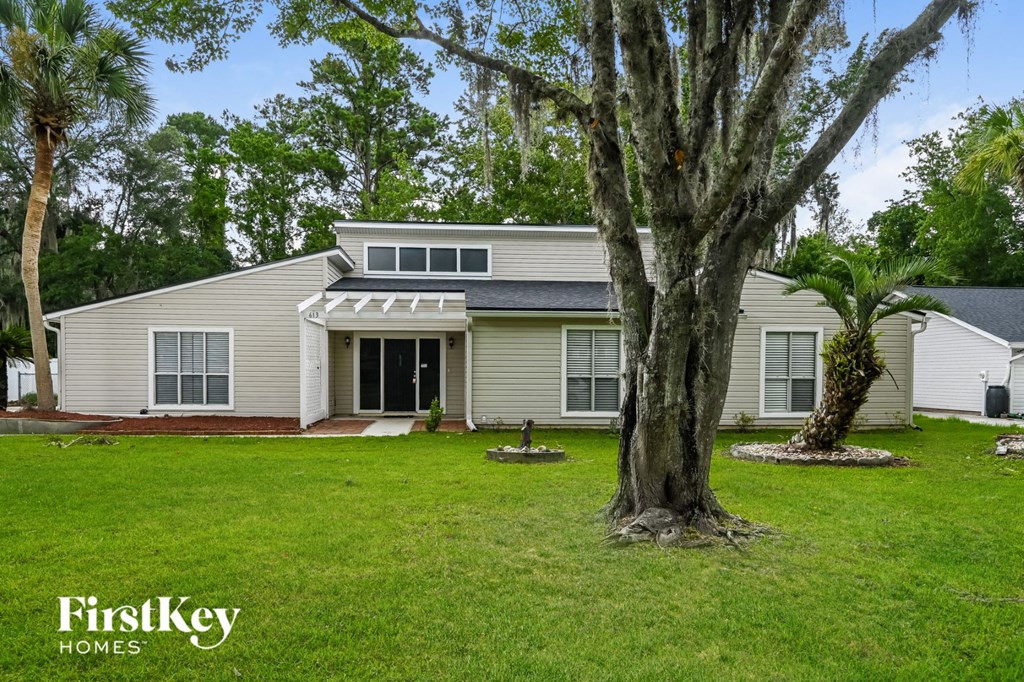 a white house with a large tree in the yard