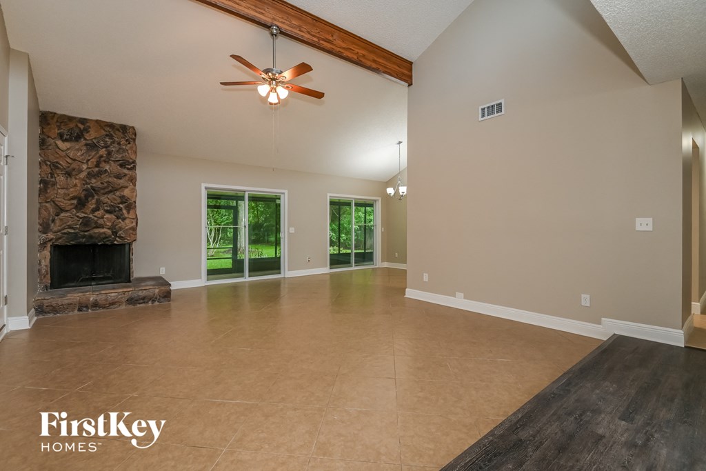 an empty living room with a fireplace and a ceiling fan