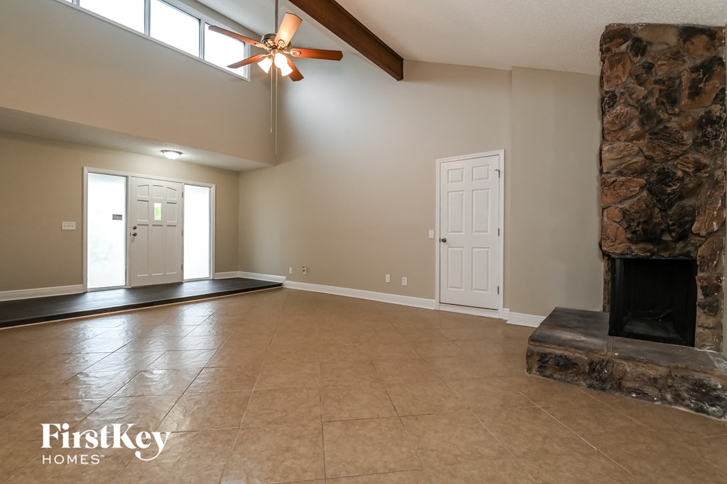 an empty living room with a fireplace and a tile floor