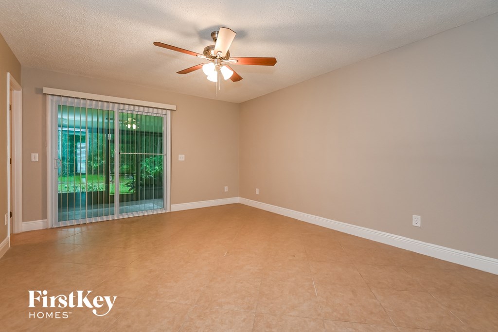 a empty living room with a large window and a ceiling fan