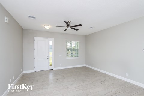 A spacious room with a ceiling fan and a door leading to a balcony.
