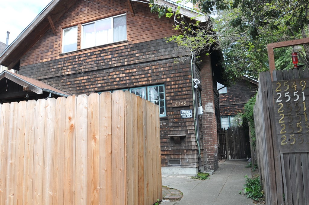 the house is behind a wooden fence and a wooden gate