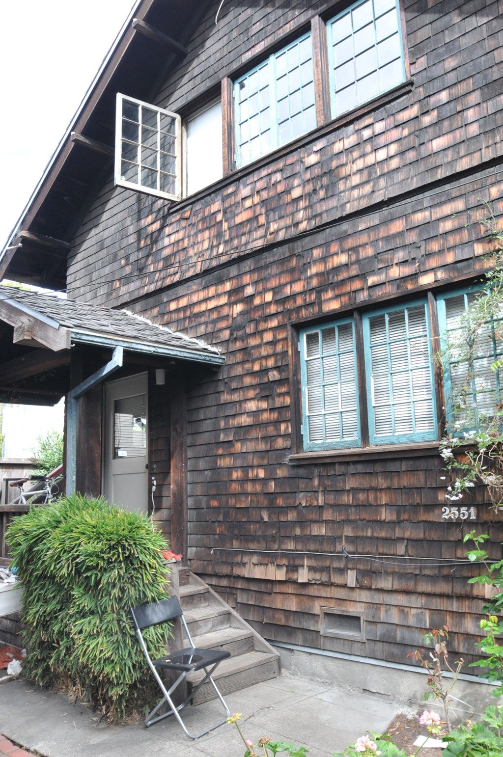 the side of a brick house with a porch and a chair