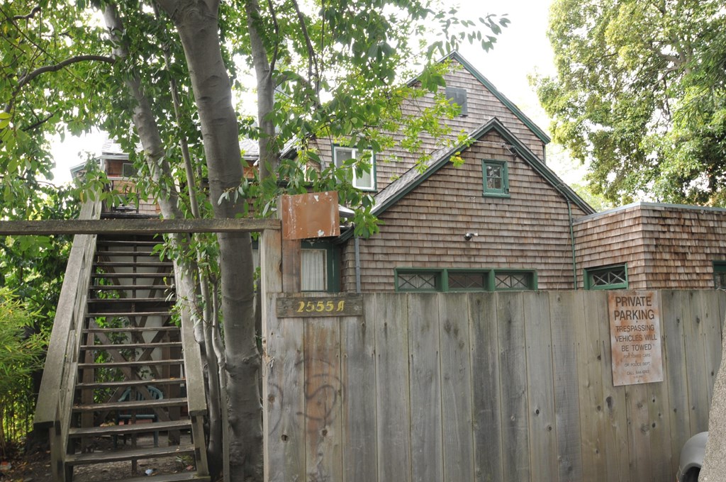 a house behind a wooden fence and a tree
