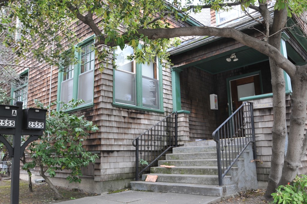 the front of a house with stairs and a tree