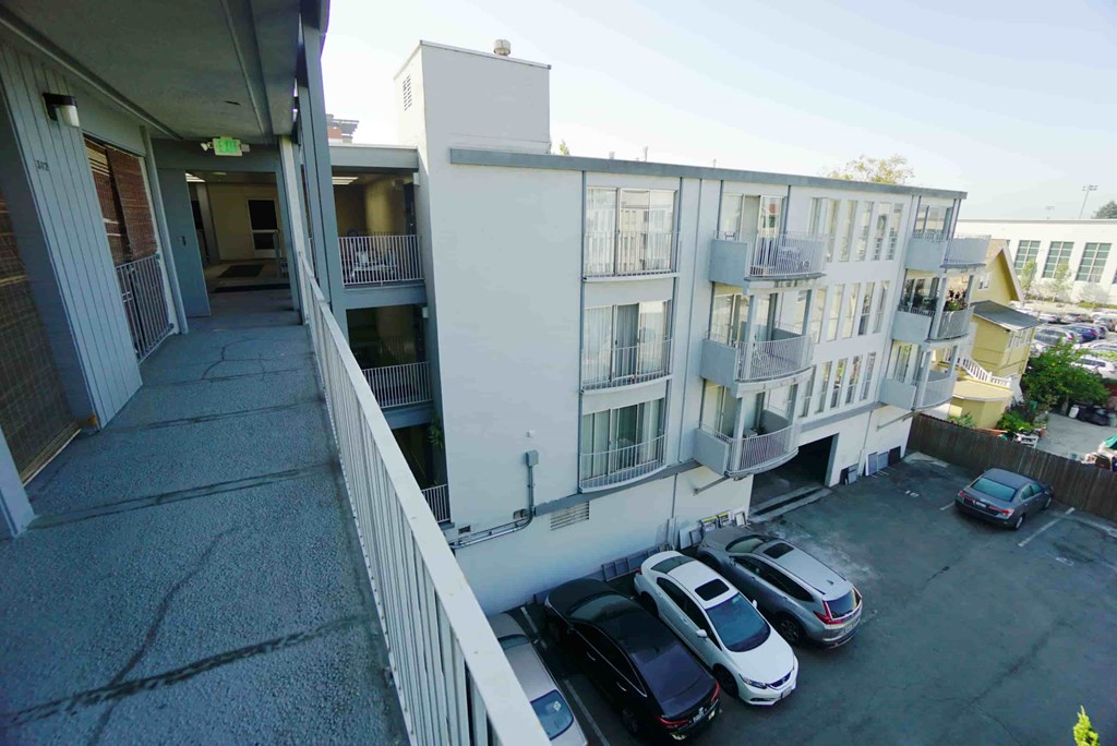 the view from the balcony of an apartment building with parked cars