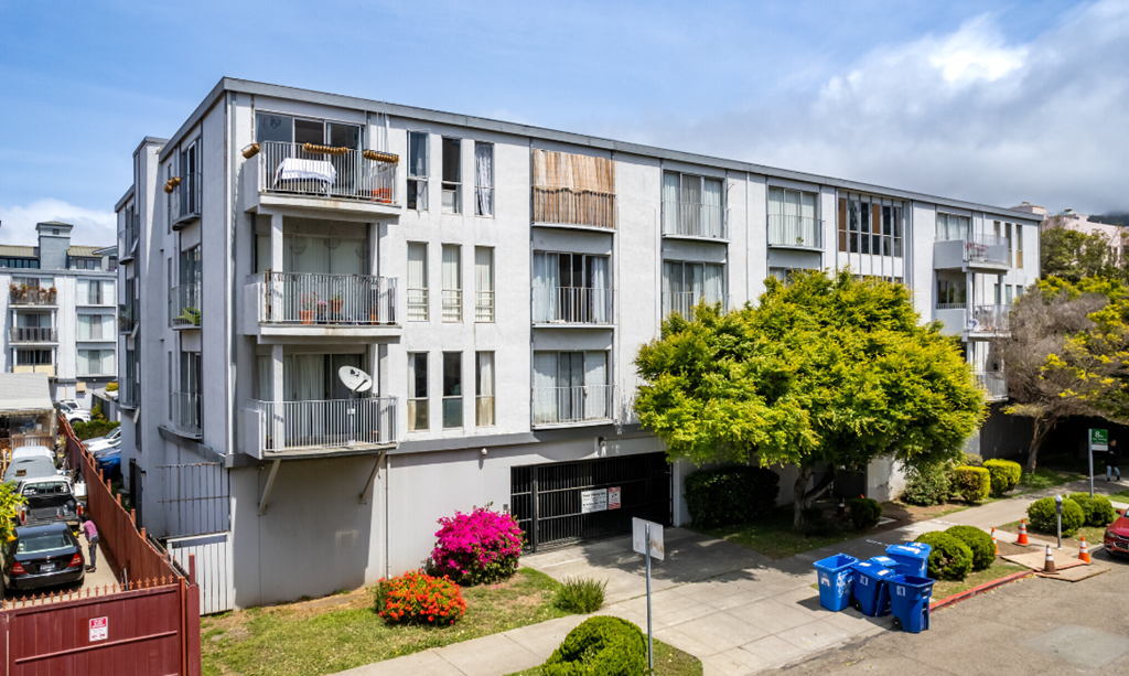 an apartment building with many balconies and a sidewalk in front