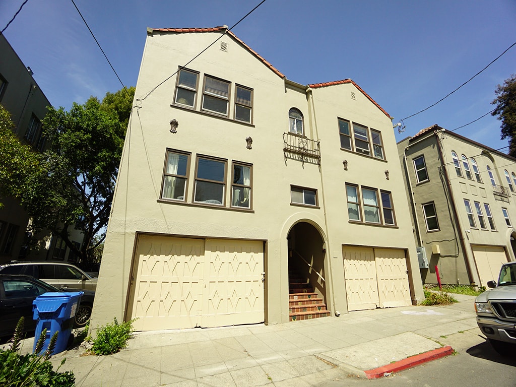 A two-story building with a garage door and a balcony on the second floor.