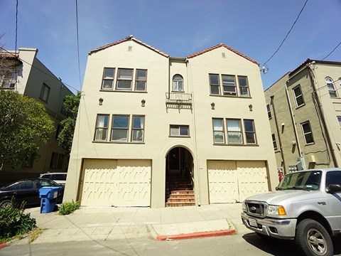 A white two-story house with a garage door and a car parked in front.