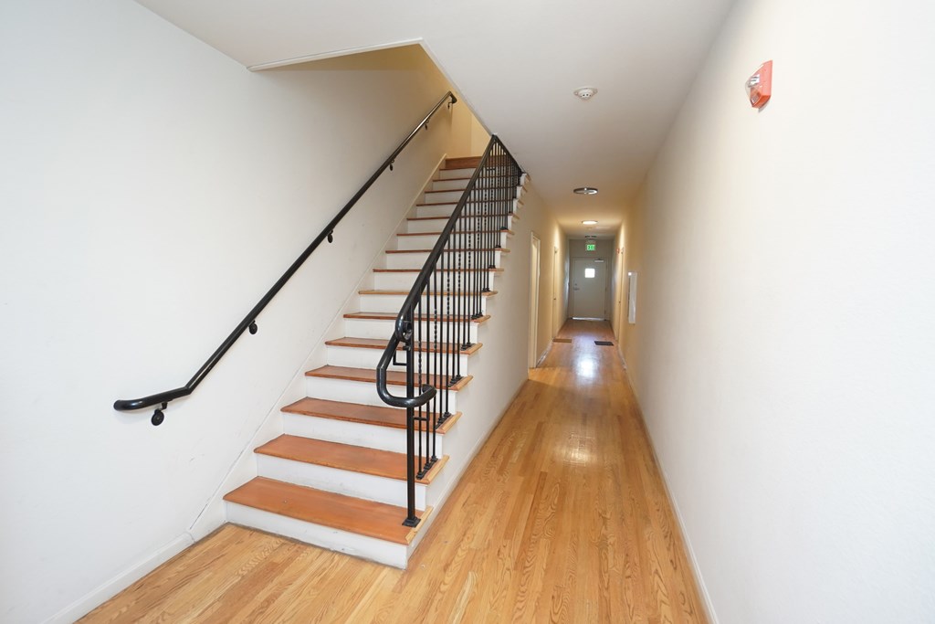 a staircase with wood floors and a railing and white walls