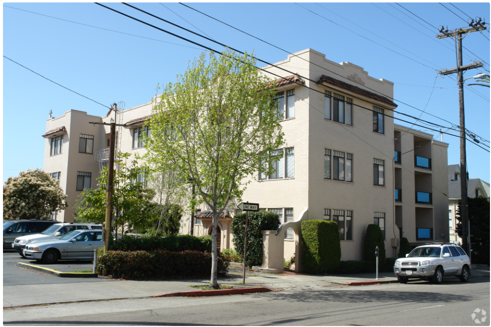 an apartment building on the corner of a street with cars