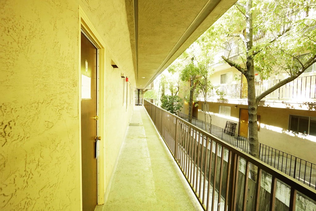 a corridor of a building with a fence and trees