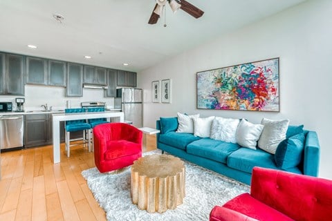 a living room with a blue couch and a kitchen in the background