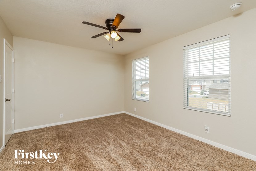 an empty living room with a ceiling fan and a window