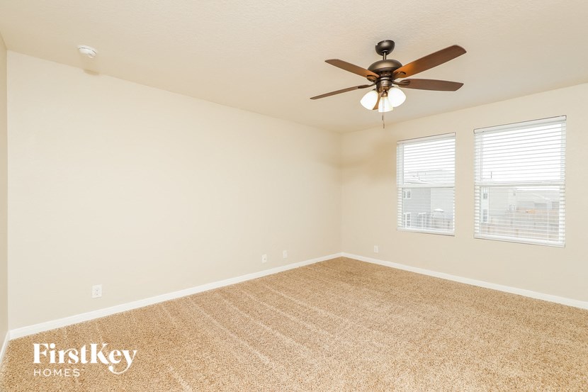 an empty room with a ceiling fan and two windows